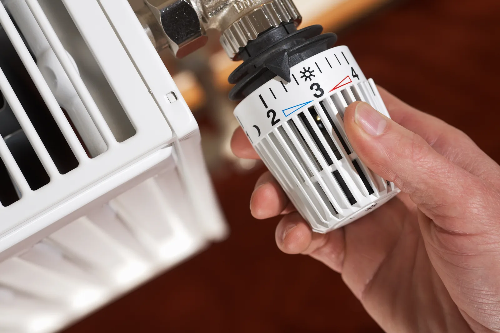 Hand am Heizkörper-Thermostat — Heizkosten im Blick